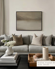 modern living room with a gray sofa, decorative pillows, and a framed artwork on the wall.