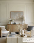 modern living room with wicker chairs, a coffee table, and a framed artwork on the wall.