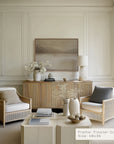 modern living room with wicker chairs, a coffee table, and a framed artwork on the wall.