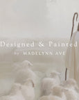 shepherd with sheep in a misty landscape, with 'designed & painted by madelynn ave' text overlay.