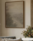 forgotten road in a dark walnut floater frame beside wooden built-in bookshelves, above a slate blue sofa with linen pillows, a floor lamp, and a vase of dried flowers and seed pods. shown in floater walnut, 30 x 40.