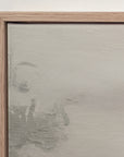close-up of the top corner of the vertical forgotten road print in a light oak floater frame against a white wall, showing the canvas edge and faint treetops softened by fog.