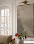 forgotten road in a light oak floater frame under a brass picture light, beside white french doors, above a camel sofa and a small vase of red flowers. shown in floater oak, 30 x 40.