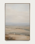 framed landscape painting of a misty field with a white structure on a white wall.