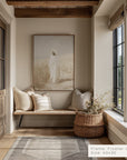 nook with wooden bench, pillows, and a woven basket with flowers, featuring a framed artwork on the wall.