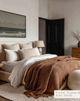 cozy bedroom with a bed, lamp, and artwork on the wall.