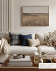 modern living room with a white sofa, decorative pillows, and a framed landscape painting on the wall.