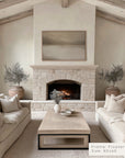 living room with stone fireplace, beige sofas, and a coffee table.