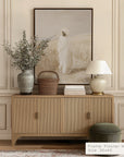 wooden sideboard with decorative items against a wall with a framed abstract painting.