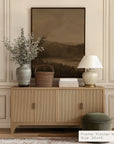 wooden cabinet with decorative items against a wall with a framed landscape painting. __lifestyleimage