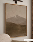 a closer view of white mountains in a light oak floater frame under a bronze picture light, beside a cream striped armchair and patterned drapes. shown in floater oak, 36 x 48.