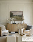 modern living room with wicker chairs, a coffee table, and a landscape painting on the wall.
