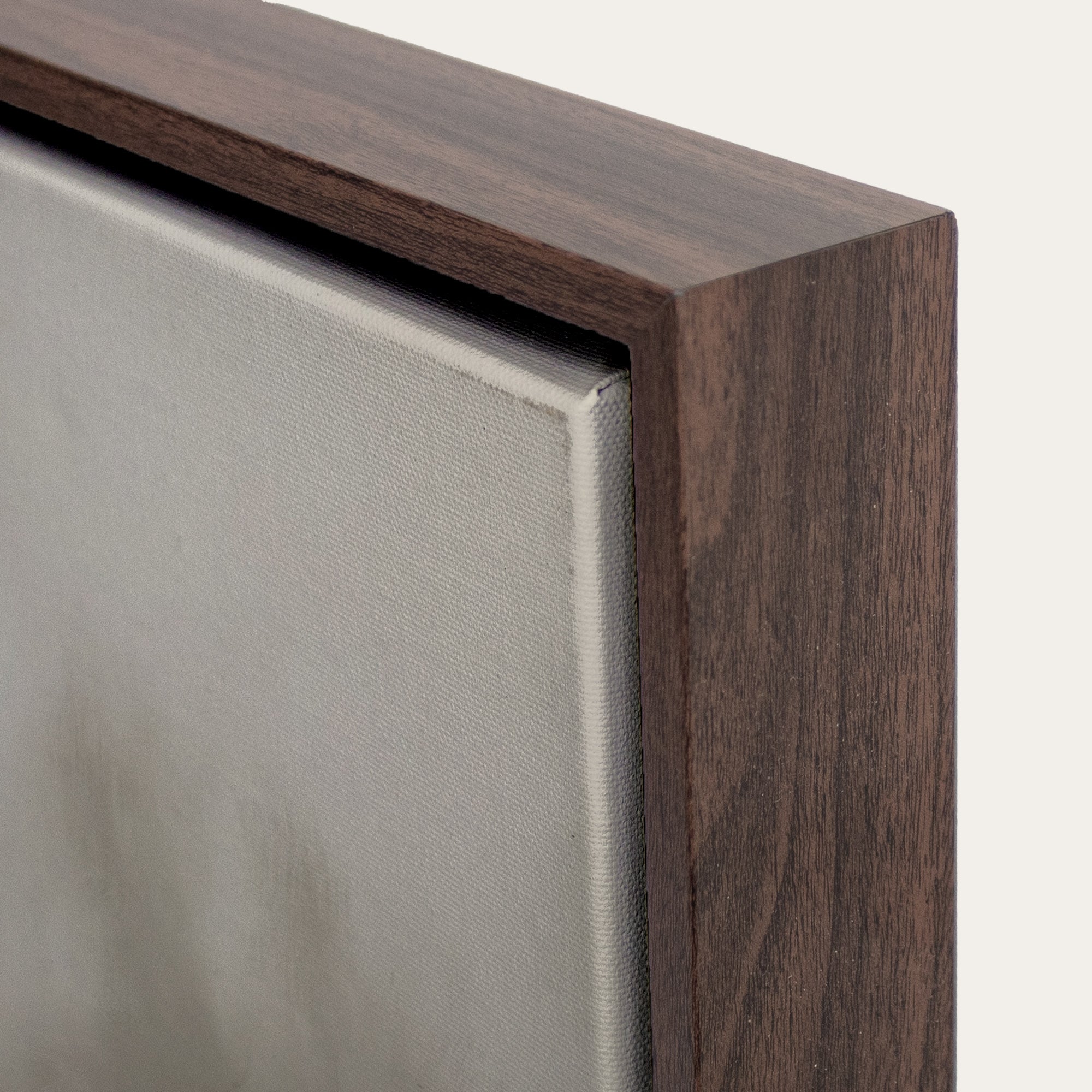 Close-up of a wooden picture frame corner with a neutral background. 