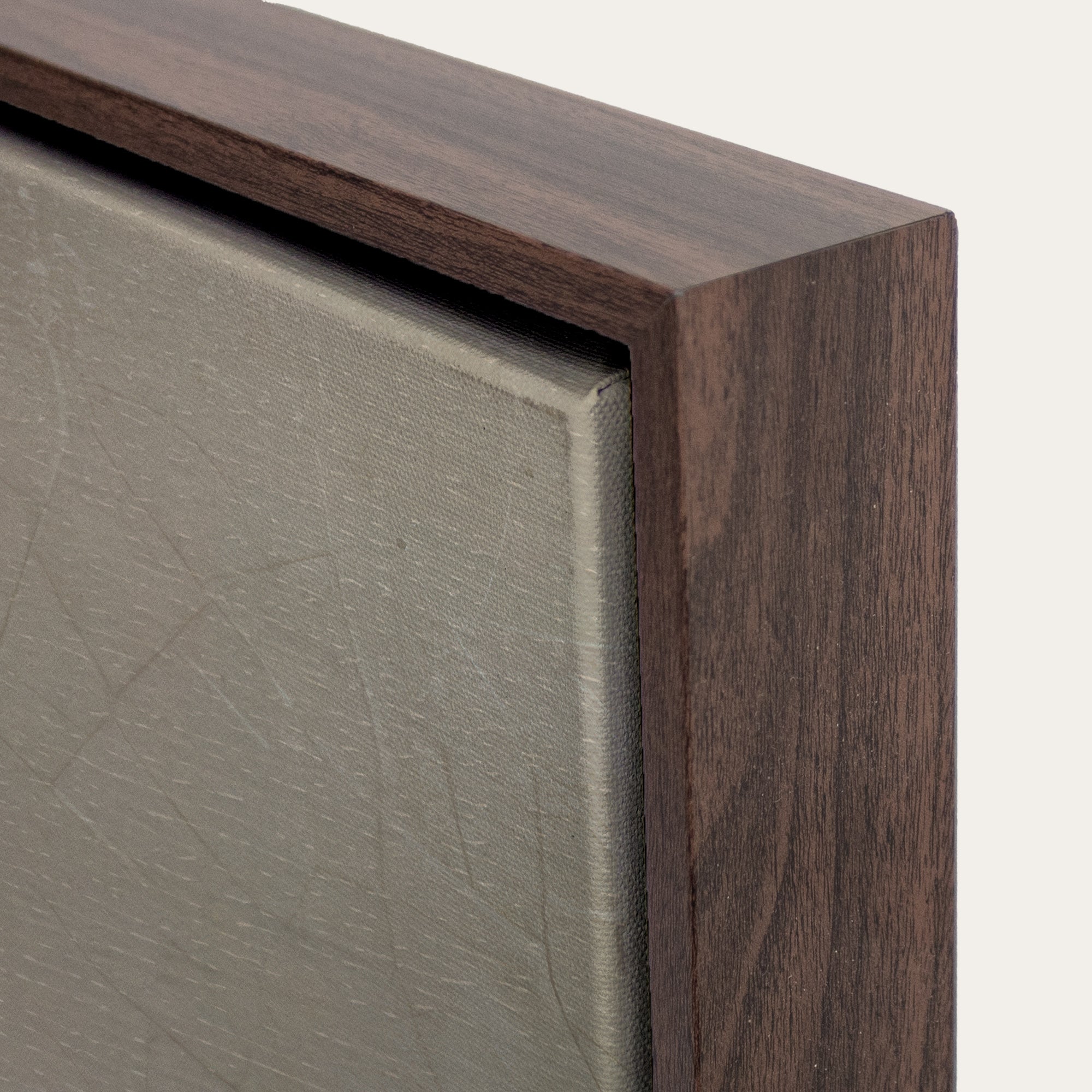 Close-up of a wooden frame corner with a textured gray surface. 