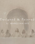 artistic depiction of a group of people sitting around a table with text 'designed & painted by madelynn ave' overlay.