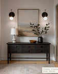 foyer with wooden console table, lamp, and artwork on a neutral wall.