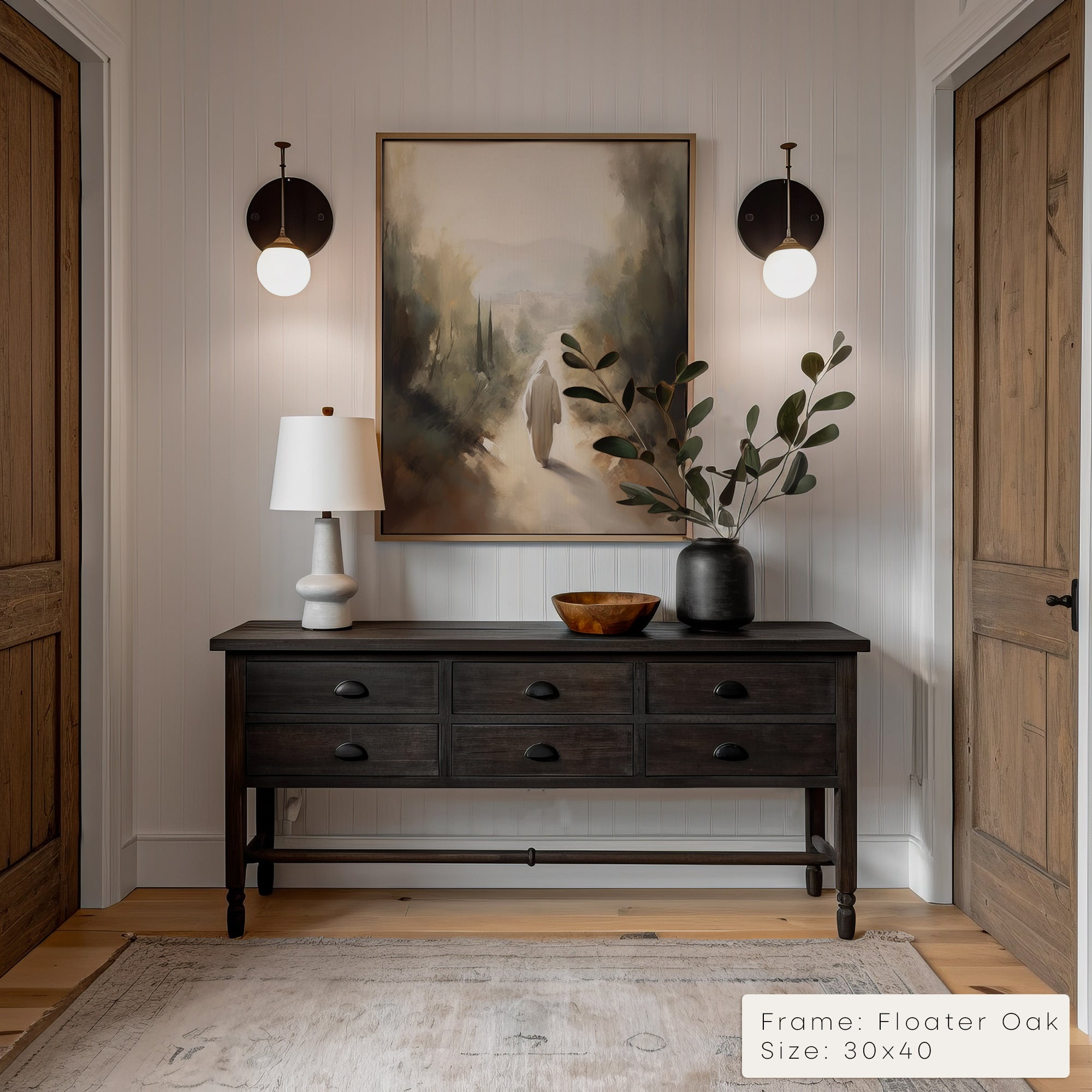 Narrow hallway with a dark wooden console table, lamp, and painting on a white wall.