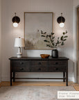 foyer with wooden console table, lamp, and artwork on a neutral wall.