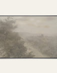 forgotten road art print in a black floater frame. a foggy road fades past a dark stand of trees in soft grays and warm stone tones, shown against a plain off-white wall. 