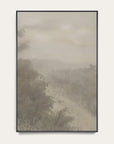 forgotten road vertical art print in a black floater frame. a foggy road fades past a dark stand of trees in soft grays and warm stone tones, shown against a plain off-white wall. 