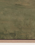 textured green surface with a signature at the bottom right corner 