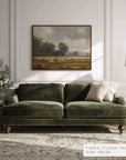 green velvet sofa in a living room with a painting on the wall and a lamp.