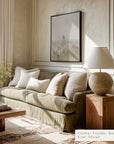 living room with a beige sofa, wooden side table, and framed artwork on the wall.