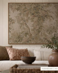 A large framed wall art print featuring a vintage-style botanical tree pattern in muted earthy tones, displayed above a cream sofa with patterned pillows in a styled living room. A small label in the bottom right reads 'FLOATER OAK | 48 x 36'.