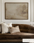 brown velvet sofa with decorative pillows in a room with framed artwork on the wall.