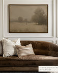 brown sofa with decorative pillows in a room with a framed landscape painting on the wall.
