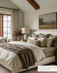 neatly made bed with pillows and a blanket in a bedroom setting.