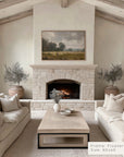 living room with stone fireplace, beige sofas, and a painting above the fireplace. __lifestyleimage