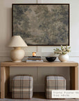 Wooden console table with lamp, books, and decorative items against a wall with a framed painting.