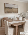 dining room with wooden table, chairs, and a framed landscape painting on the wall.