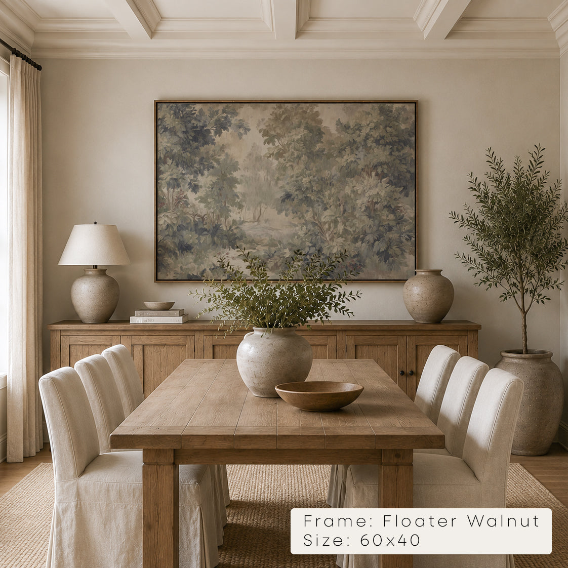 A large framed landscape art print hangs on a beige wall above a wooden dining table and chairs in a styled dining room. The print depicts a soft, muted forest scene in blue-gray, beige, and brown tones. __lifestyleImage