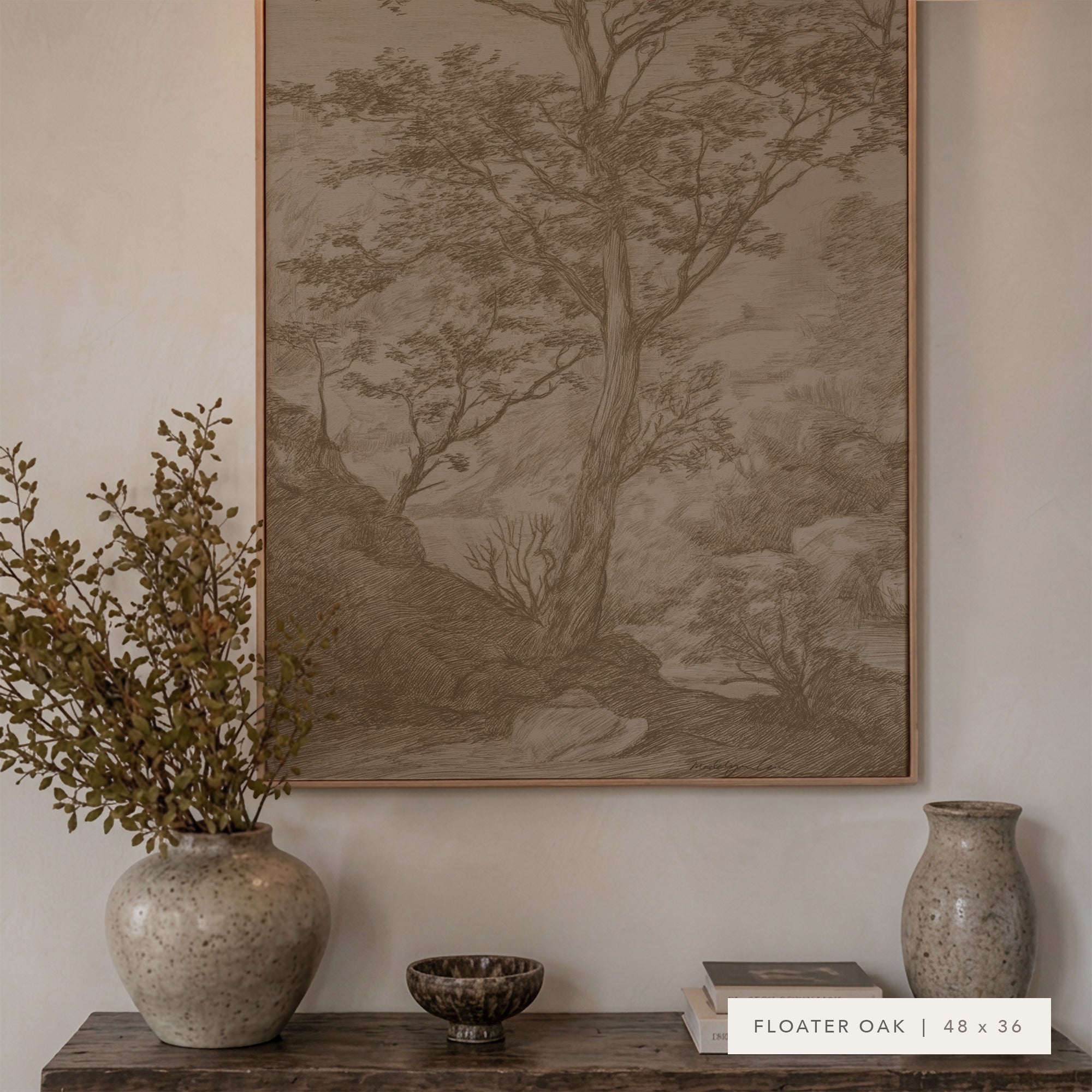 A framed landscape art print featuring a detailed tree and forest scene in muted sepia tones, displayed on a wall above a wooden console table styled with ceramic vases and a small bowl. A label at the bottom right reads 'FLOATER OAK | 48 x 36'.