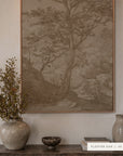 A framed landscape art print featuring a detailed tree and forest scene in muted sepia tones, displayed on a wall above a wooden console table styled with ceramic vases and a small bowl. A label at the bottom right reads 'FLOATER OAK | 48 x 36'.
