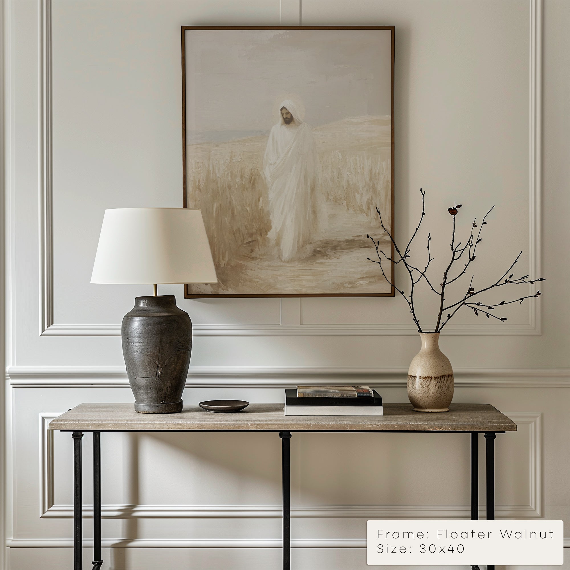 Decorative interior setting with a table, lamp, and vase against a wall with framed art.