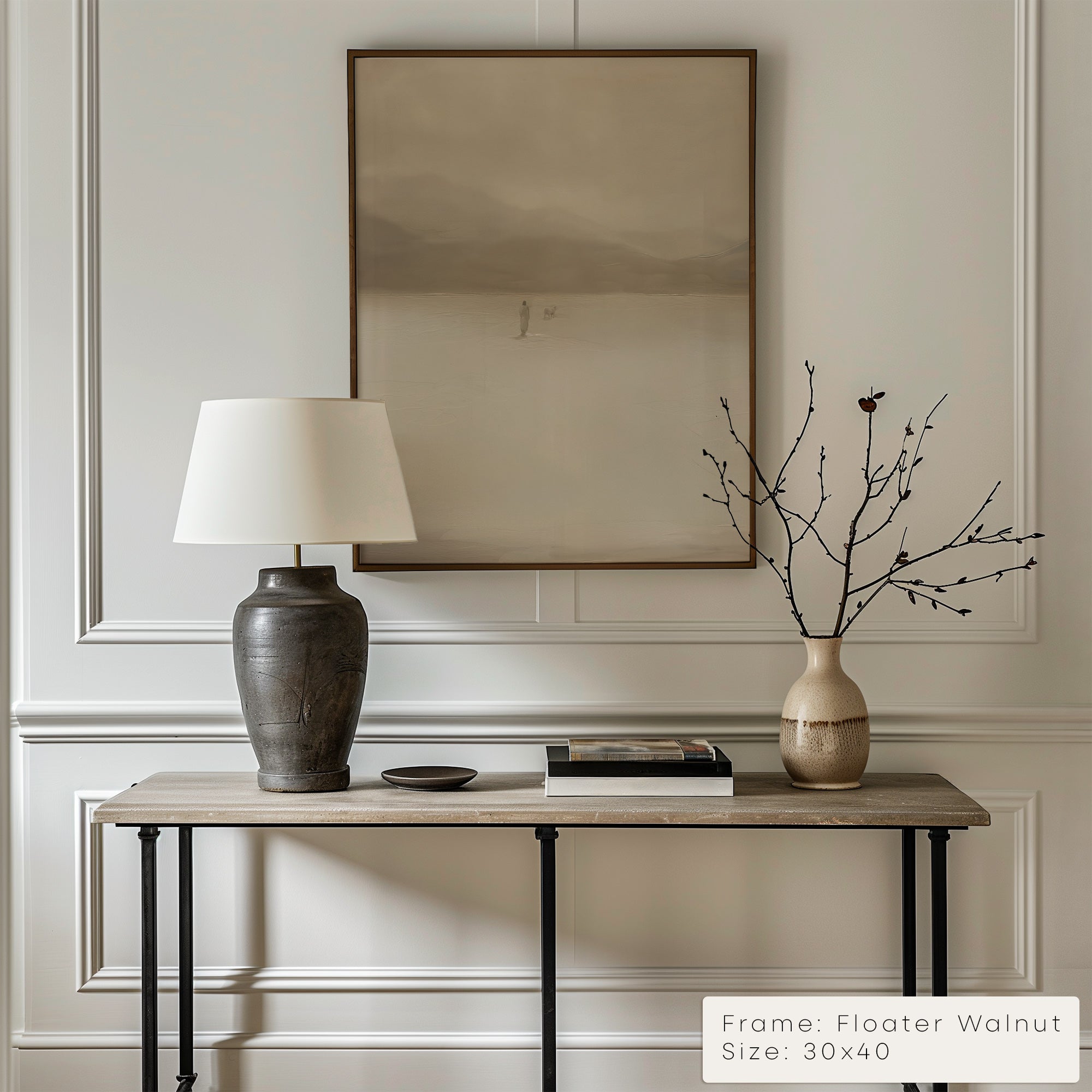 Decorative table with lamp, vase, and branches against a wall with a framed picture. __lifestyleImage