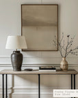 decorative table with lamp, vase, and branches against a wall with a framed picture. __lifestyleimage