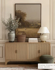 wooden sideboard with decorative items against a wall with a framed landscape painting. __lifestyleimage