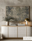 modern interior with a sideboard, decorative items, and a large framed painting on a textured wall.