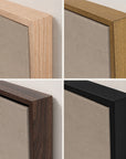 four-panel close-up of the top corner of white mountains in each floater frame finish: light oak, gold, walnut, and black, hung against an off-white wall, with the crackled sepia sky of the artwork inside.