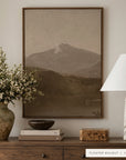 white mountains in a dark walnut floater frame above a wooden dresser with a vase of white blossoms, a dark bowl on stacked books, a burl wood box, and a marbled table lamp. shown in floater walnut, 30 x 40.