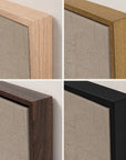 four-panel close-up of the top corner of the vertical white mountains print in each floater frame finish: light oak, gold, walnut, and black, hung against an off-white wall, with the crackled sepia sky of the artwork inside.